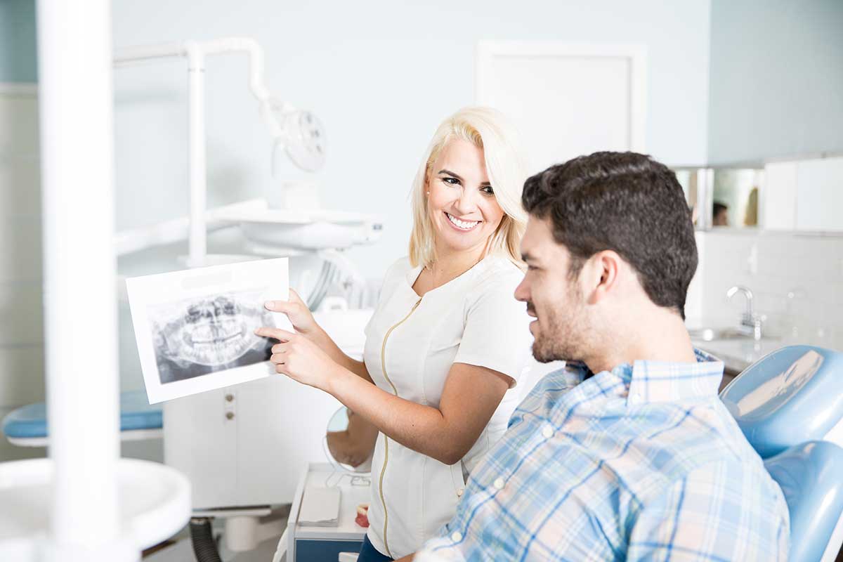 Cute female dentist showing x-rays to male patient in dental clinic