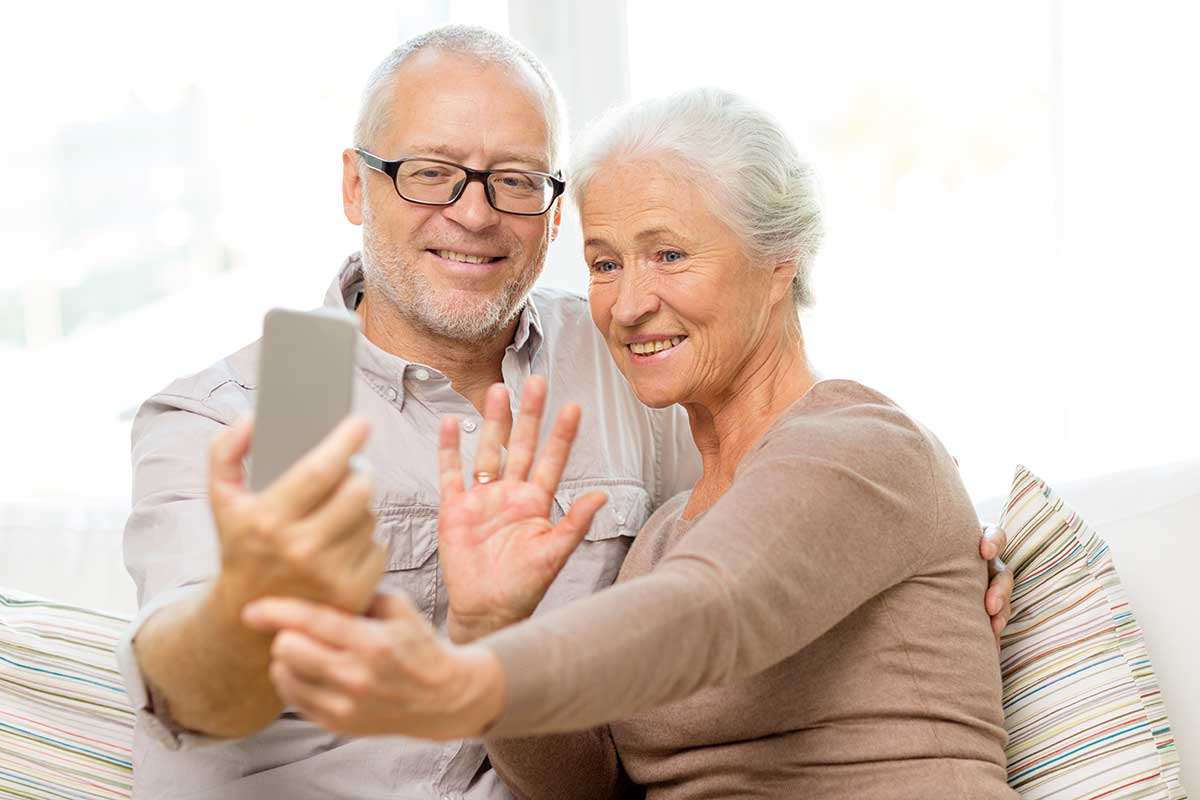 Happy senior couple with smartphone at home